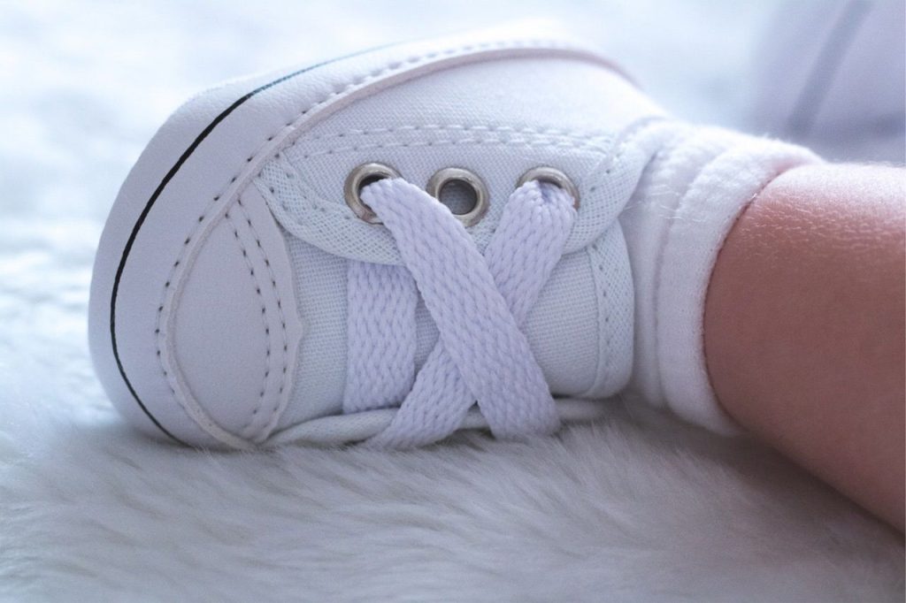 Close-up of a white baby shoe on a soft, fluffy surface, symbolizing new beginnings.